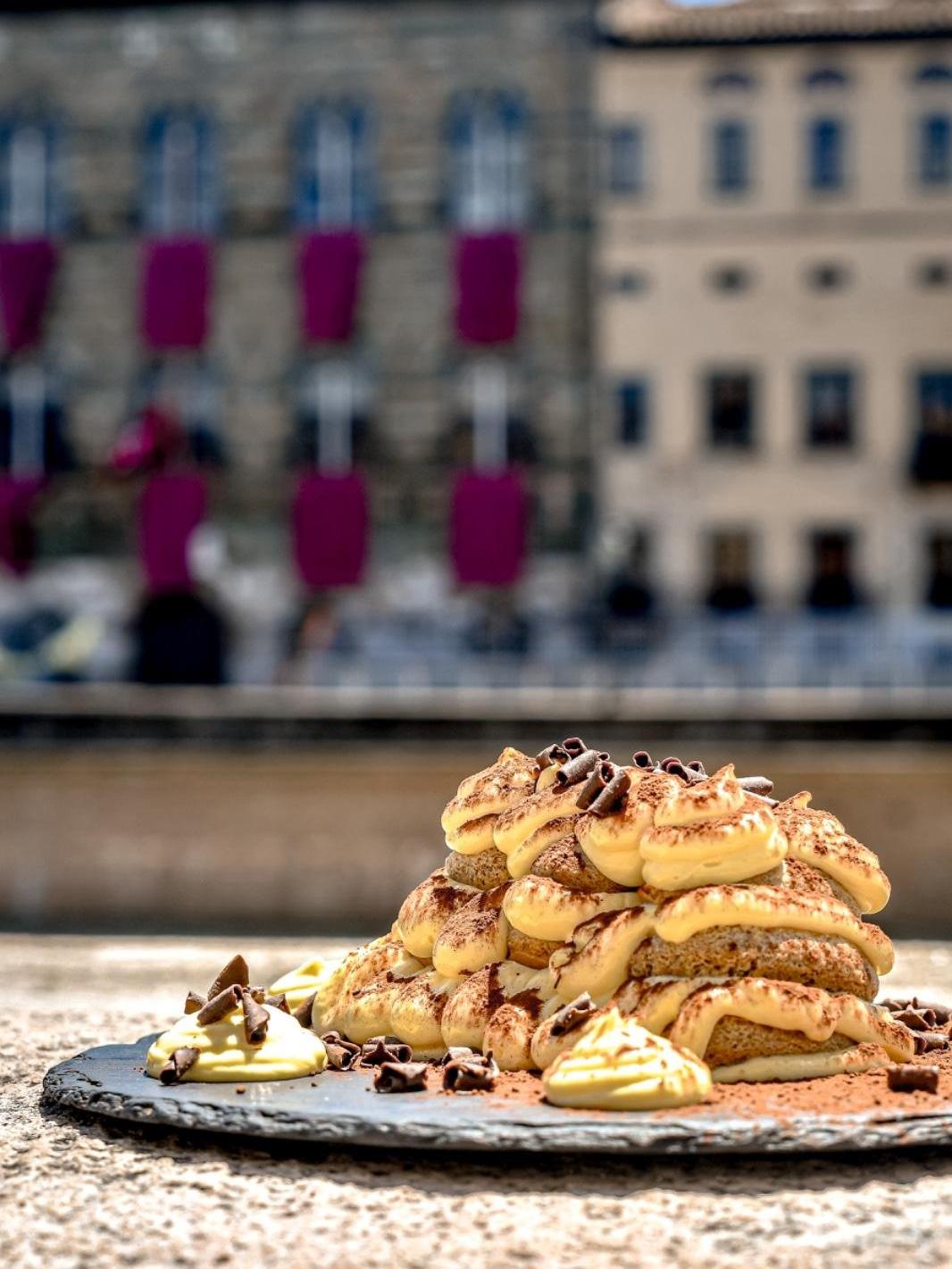 Tiramisù with cream and crumble on a slate plate resting on the Arno river wall