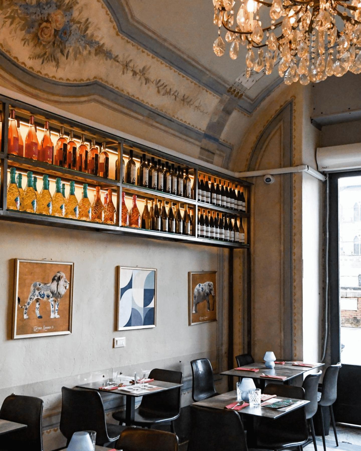 The Misù dining room: crystal chandelier, frescoed ceiling, backlit wall of bottles and dark tables