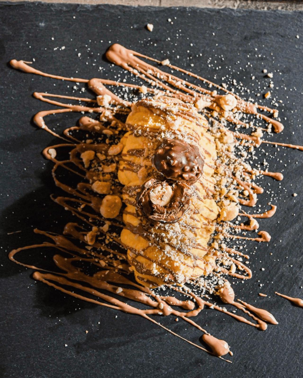 Ferrero Rocher tiramisù with chocolate and hazelnuts drizzled on the slate