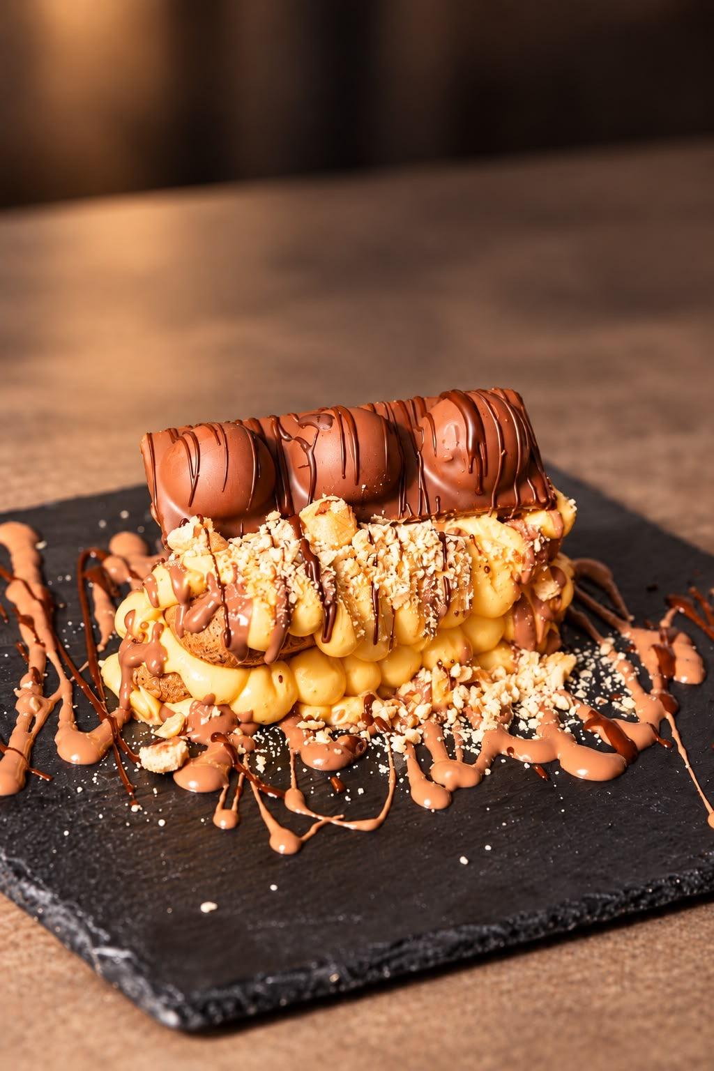 Kinder Bueno tiramisù with the bars on top and chocolate drizzled on the slate