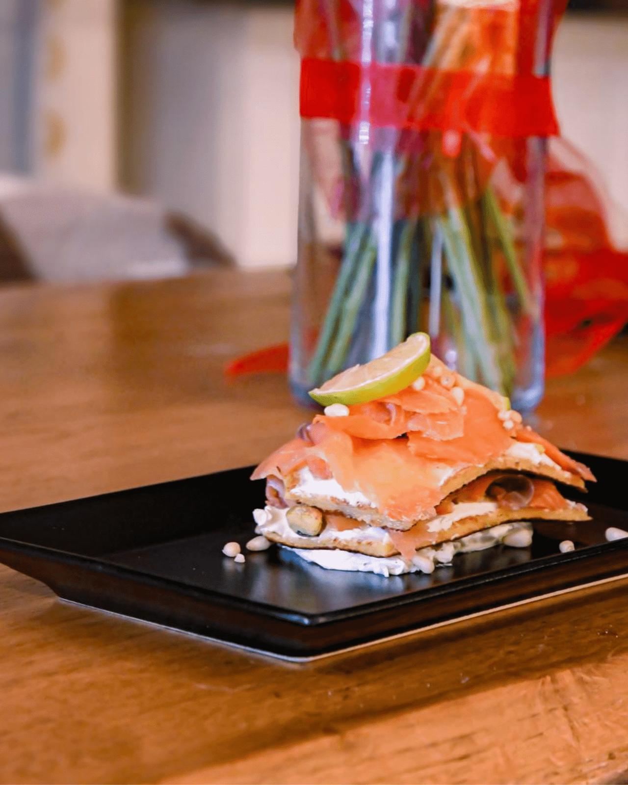 Savoury tiramisù with salmon, Philadelphia and lime on a black plate